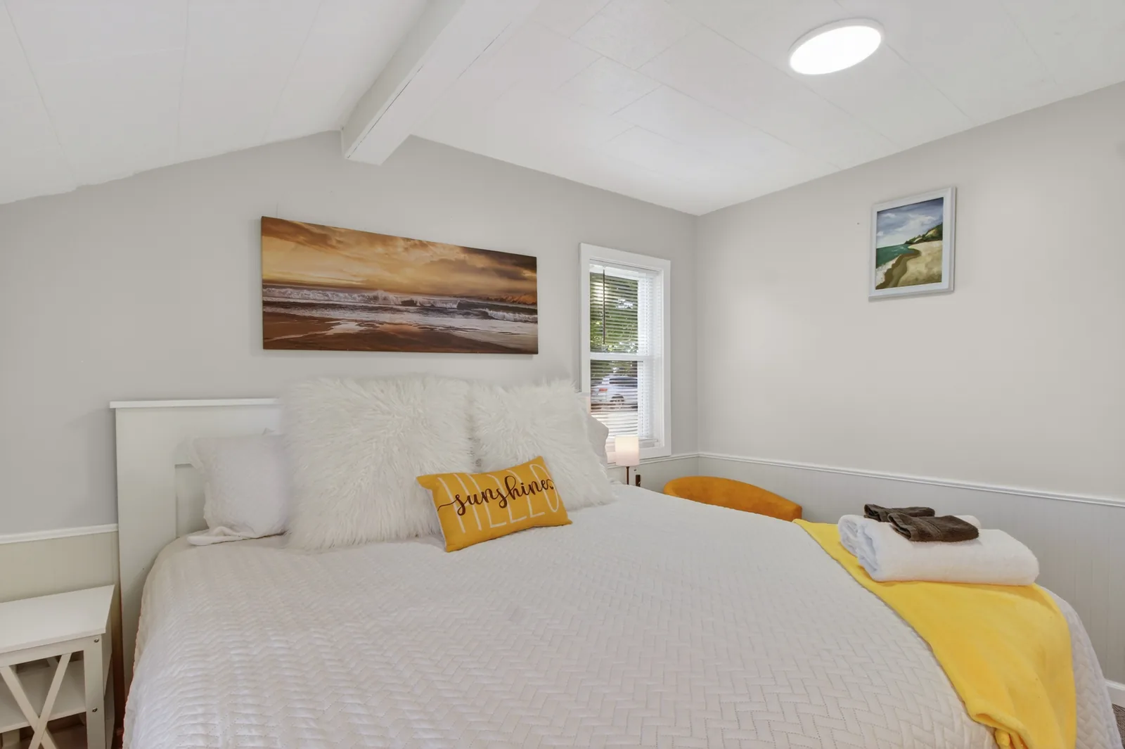 Cabin 7 queen bedroom with sunshine pillow and coastal artwork
