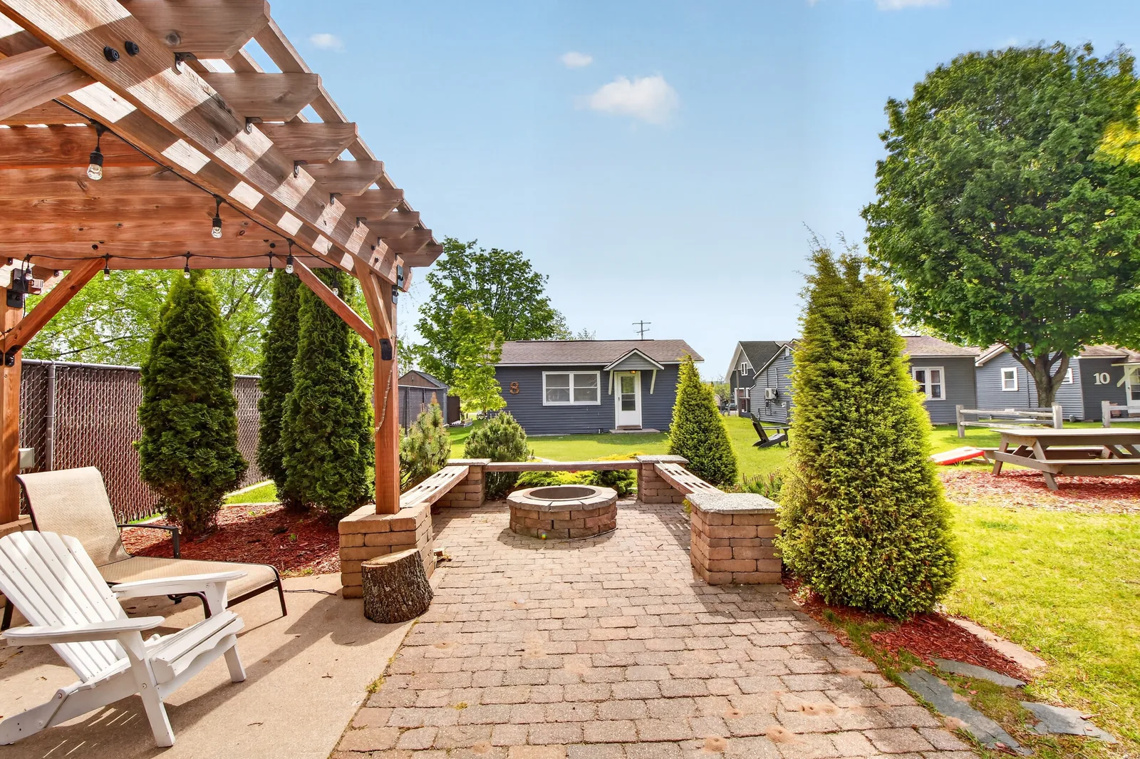 Pergola lounge with fire pit and stone benches overlooking the resort grounds